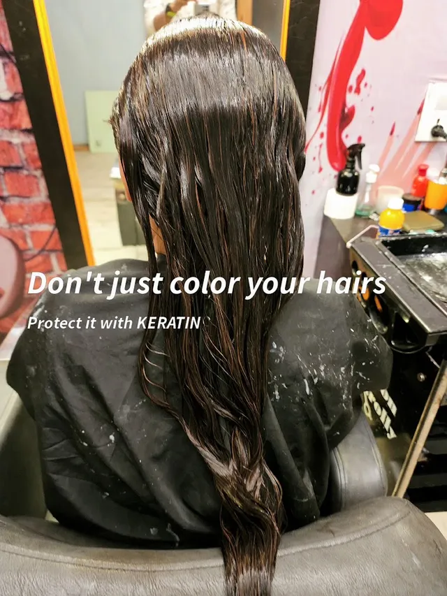 A client leans back into a wash chair, hair damp and freshly coloured with visible highlights, during a keratin treatment at a styling station.